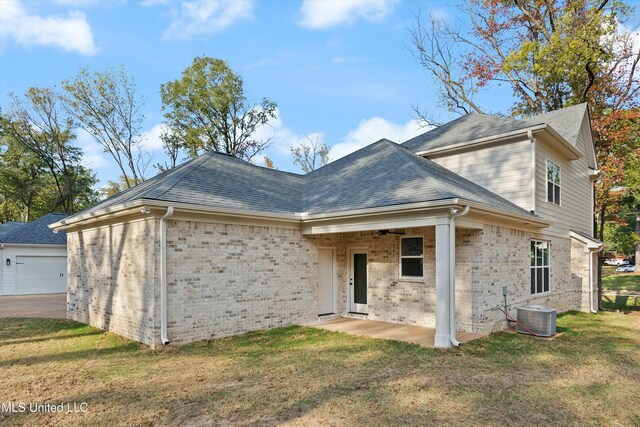 rear view of house featuring a yard, cooling unit, and a garage