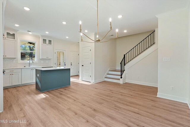 kitchen featuring hanging light fixtures, a kitchen island, tasteful backsplash, light hardwood / wood-style flooring, and white cabinets