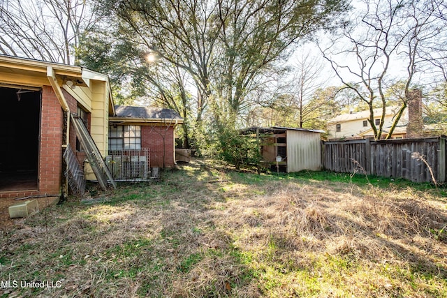 view of yard featuring fence, an outdoor structure, and a storage shed