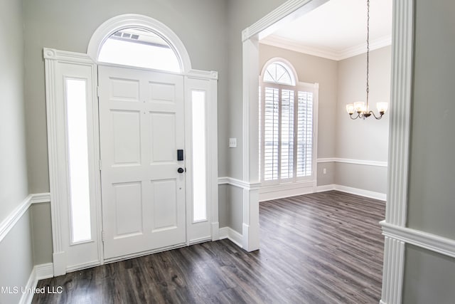 entrance foyer with dark wood-type flooring, an inviting chandelier, and ornamental molding