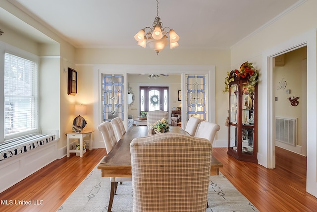 dining room featuring an inviting chandelier, ornamental molding, and light wood-type flooring