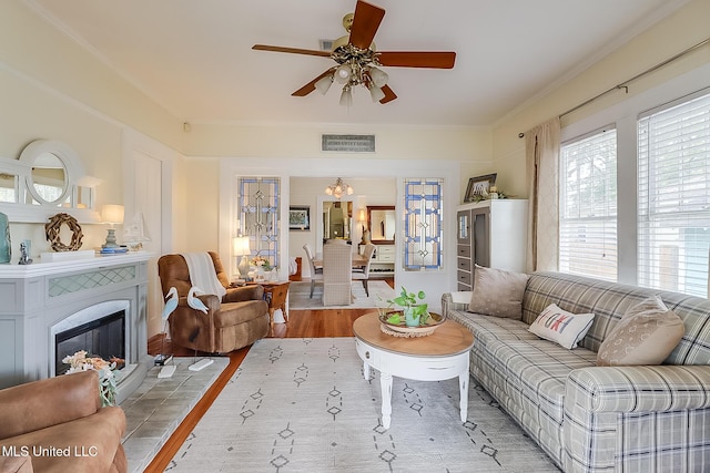 living room with hardwood / wood-style floors, crown molding, and ceiling fan