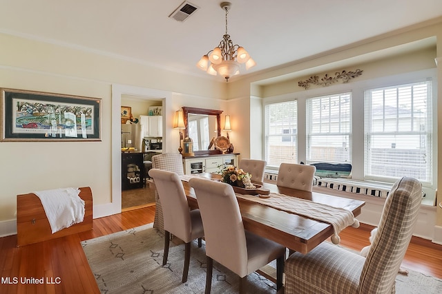 dining space with hardwood / wood-style flooring and an inviting chandelier