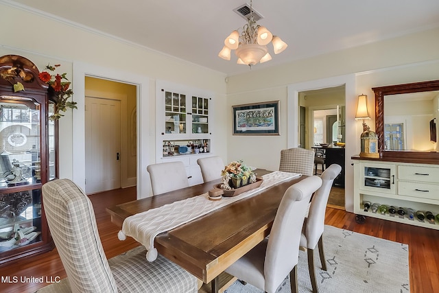 dining room featuring dark wood-type flooring, ornamental molding, and a notable chandelier