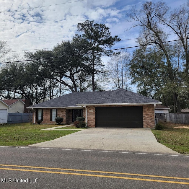 view of front of property featuring driveway, brick siding, fence, and a front yard