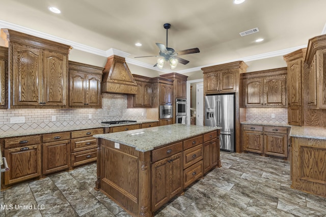 705 Brookwood Cir, Brandon, MS 39042 - kitchen featuring appliances with stainless steel finishes, a ceiling fan, premium range hood, decorative backsplash, and a center island