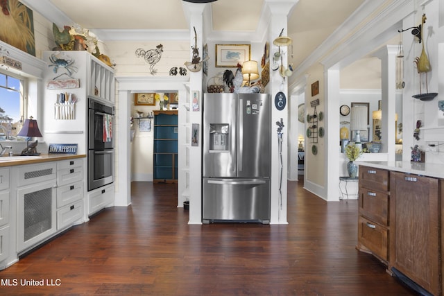 kitchen featuring multiple ovens, dark hardwood / wood-style floors, stainless steel fridge, white cabinets, and ornamental molding