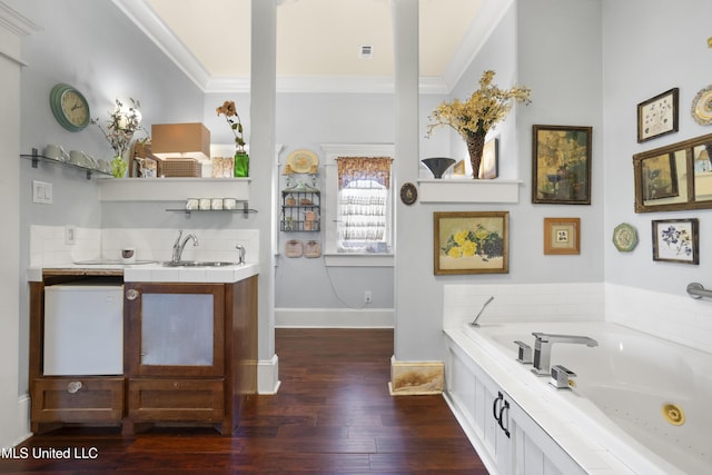 bathroom with a washtub, wood-type flooring, vanity, and ornamental molding