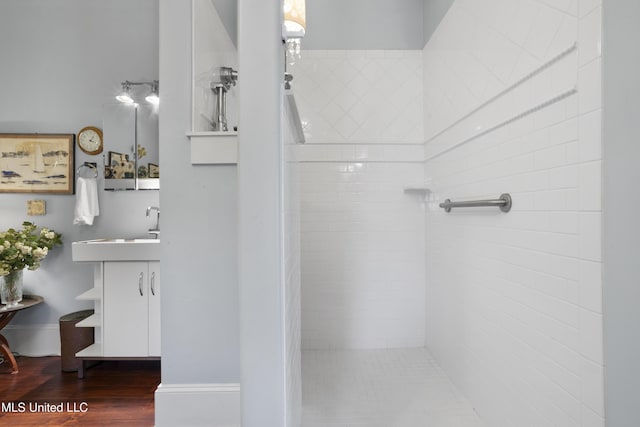 bathroom with hardwood / wood-style floors, vanity, and a tile shower