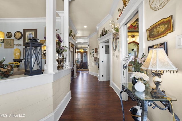 hallway featuring dark hardwood / wood-style floors, ornate columns, and crown molding