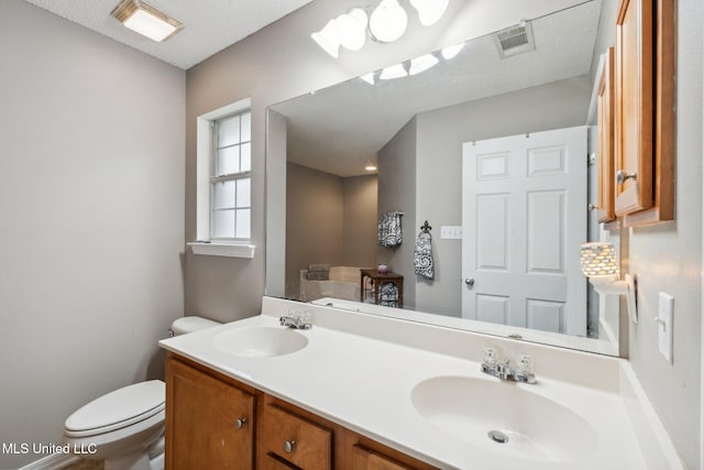 bathroom with vanity, a textured ceiling, and toilet