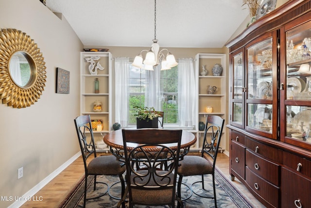 dining room with hardwood / wood-style floors, vaulted ceiling, and a notable chandelier