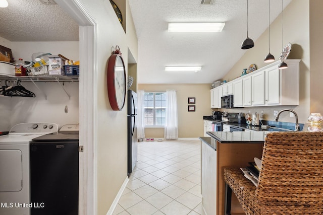 kitchen featuring washing machine and dryer, a textured ceiling, lofted ceiling, white cabinets, and black appliances