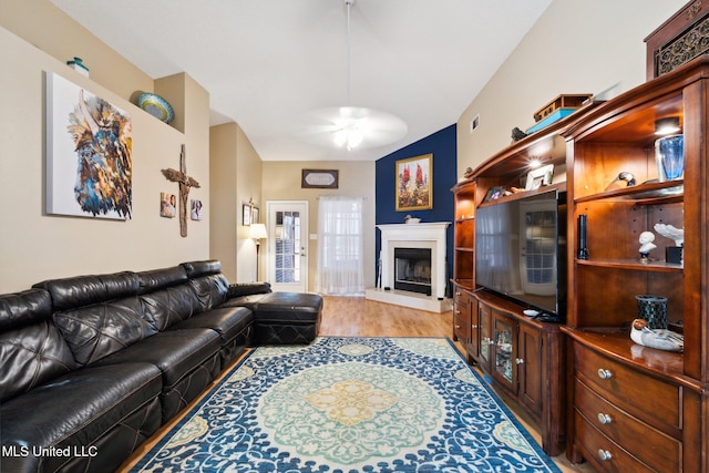 living room featuring ceiling fan, wood-type flooring, and lofted ceiling