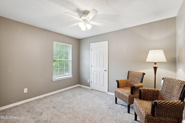 sitting room with a textured ceiling, light colored carpet, and ceiling fan