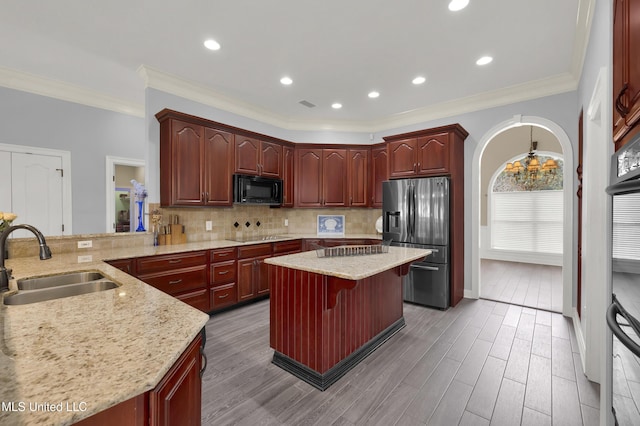 kitchen with a sink, tasteful backsplash, black appliances, and a breakfast bar