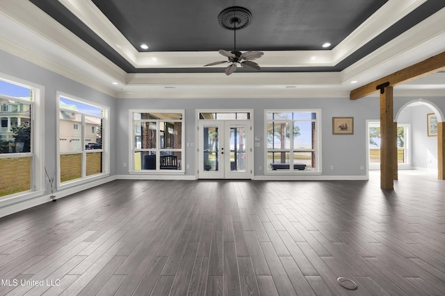 unfurnished living room featuring a raised ceiling, french doors, and dark wood-type flooring