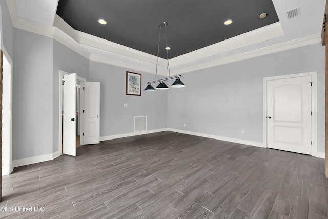 unfurnished dining area featuring a tray ceiling, crown molding, wood finished floors, and visible vents