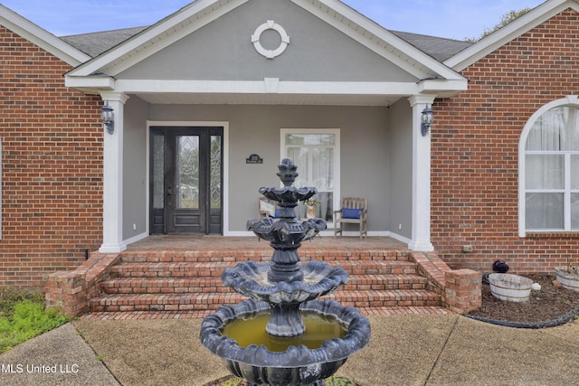 doorway to property featuring brick siding and roof with shingles