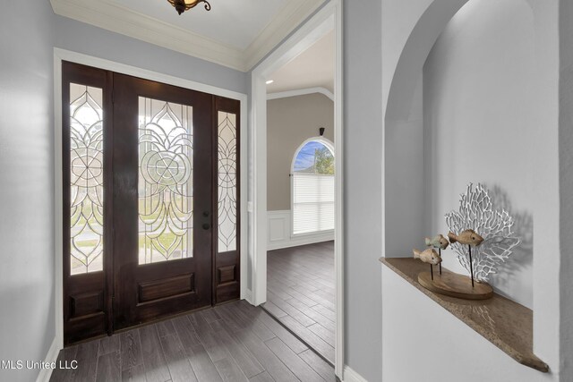 foyer entrance with a wainscoted wall, wood finished floors, arched walkways, crown molding, and a decorative wall