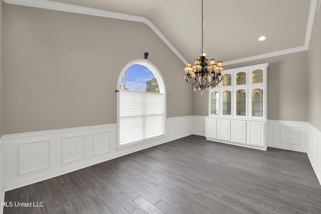 unfurnished dining area with an inviting chandelier, dark wood-style flooring, ornamental molding, vaulted ceiling, and wainscoting