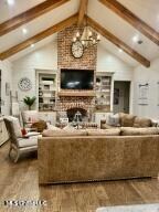 living room featuring a chandelier, vaulted ceiling with beams, hardwood / wood-style flooring, and a fireplace