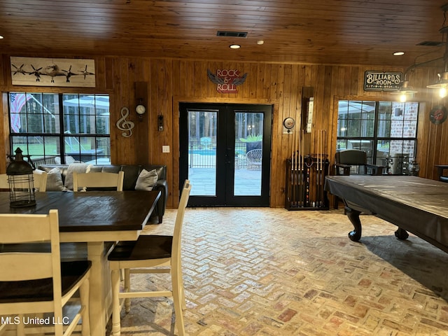 dining area featuring billiards, wooden ceiling, wooden walls, and french doors