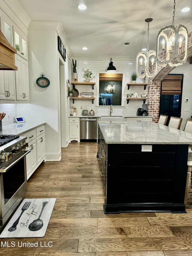 kitchen with backsplash, stainless steel appliances, light hardwood / wood-style flooring, white cabinets, and a chandelier