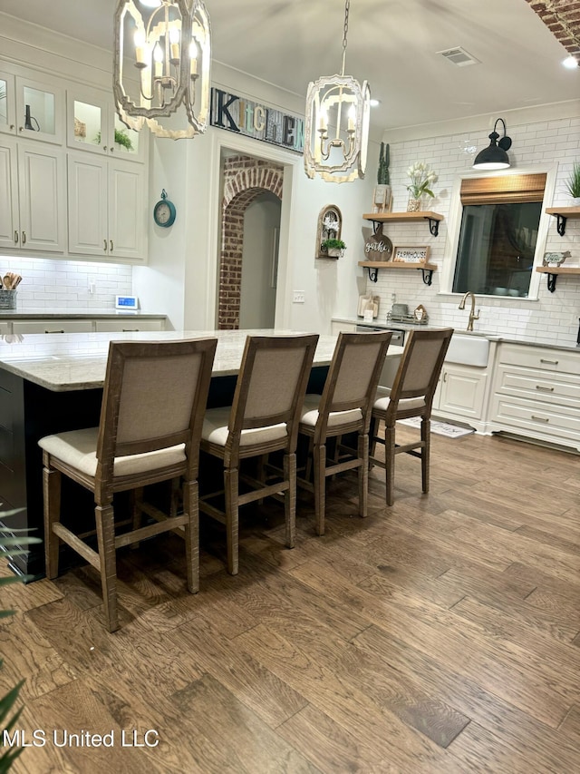 interior space with white cabinets, decorative light fixtures, dark hardwood / wood-style flooring, and tasteful backsplash