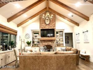 living room featuring hardwood / wood-style flooring, vaulted ceiling with beams, a fireplace, and an inviting chandelier