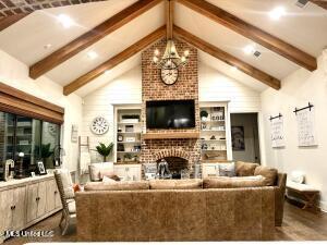 living room featuring hardwood / wood-style flooring, a fireplace, lofted ceiling with beams, and an inviting chandelier