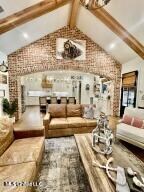 living room with vaulted ceiling with beams and brick wall