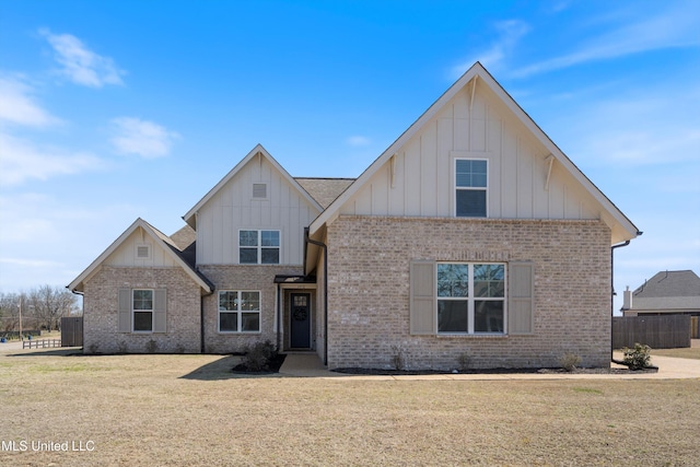 view of front facade with brick siding, board and batten siding, a front yard, and fence