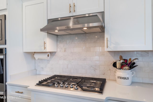 kitchen featuring under cabinet range hood, light countertops, decorative backsplash, appliances with stainless steel finishes, and white cabinetry