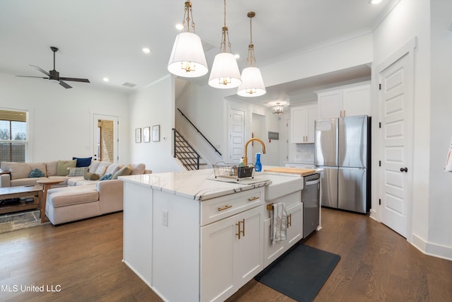 kitchen with light stone counters, stainless steel appliances, dark wood-type flooring, pendant lighting, and white cabinetry