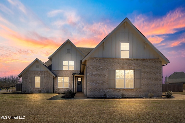 traditional-style home featuring brick siding, a lawn, and board and batten siding