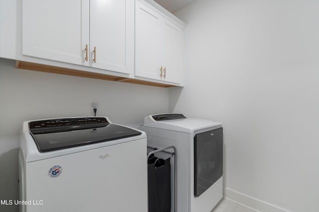 washroom with cabinet space, separate washer and dryer, and baseboards