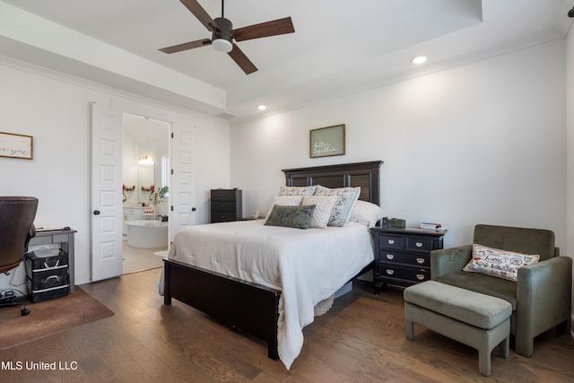 bedroom with wood finished floors, recessed lighting, ceiling fan, a raised ceiling, and connected bathroom