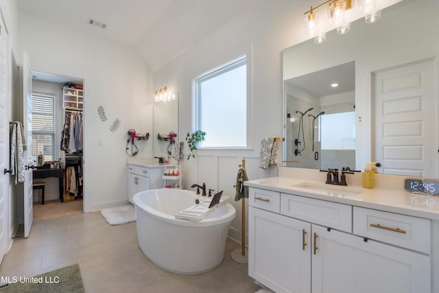 bathroom with a walk in closet, a soaking tub, vanity, and a stall shower