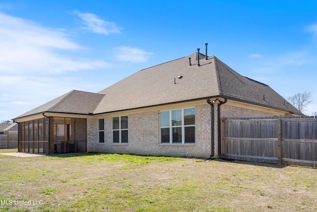 back of property featuring brick siding, a lawn, fence, and a shingled roof