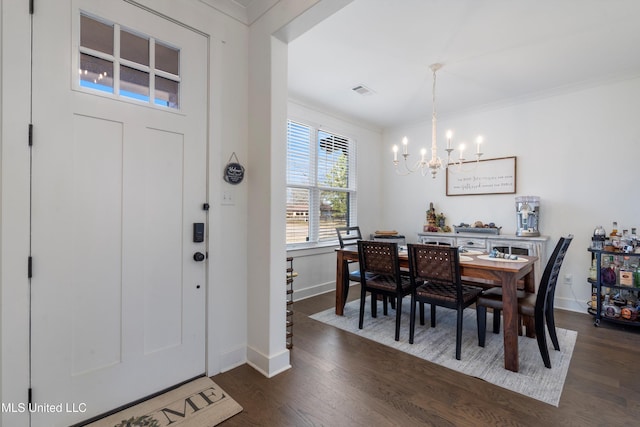 foyer entrance with baseboards, dark wood-type flooring, a chandelier, and crown molding