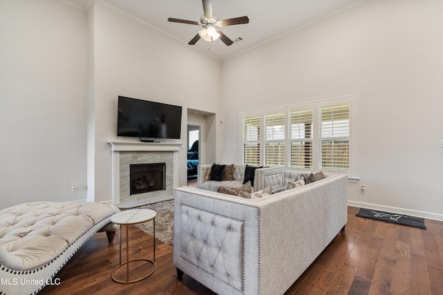 living room with ornamental molding, dark wood-type flooring, a tile fireplace, and ceiling fan