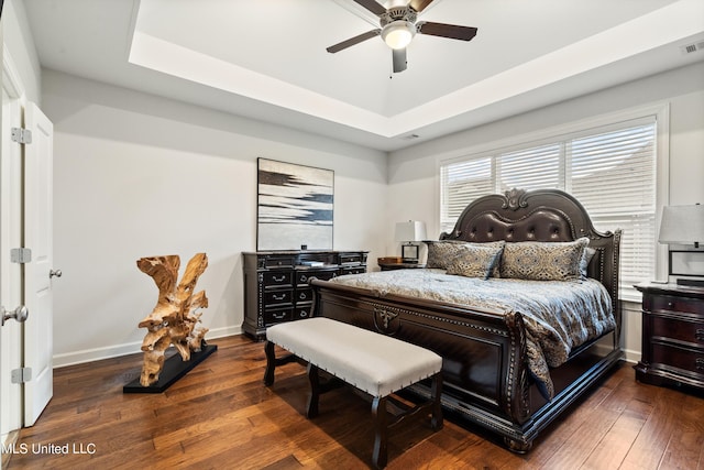 bedroom featuring ceiling fan, a raised ceiling, and dark hardwood / wood-style floors