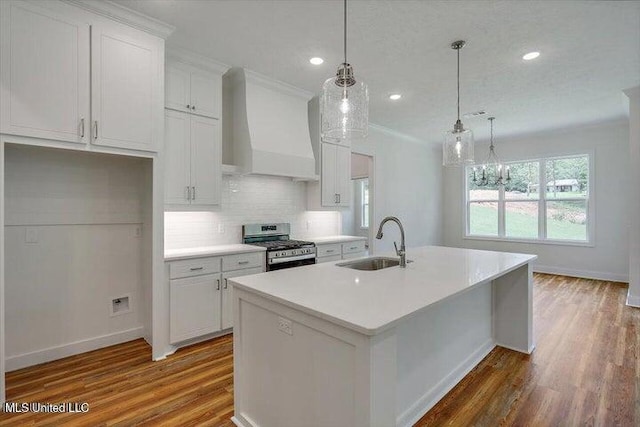 kitchen featuring a center island with sink, sink, gas range, and wood-type flooring