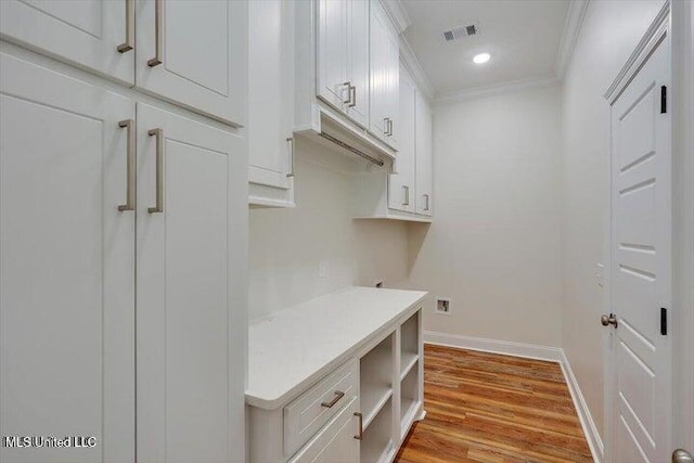 interior space with cabinets, light hardwood / wood-style floors, and crown molding