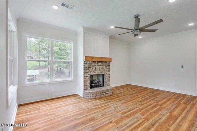 unfurnished living room with ornamental molding, a fireplace, a textured ceiling, ceiling fan, and light hardwood / wood-style flooring