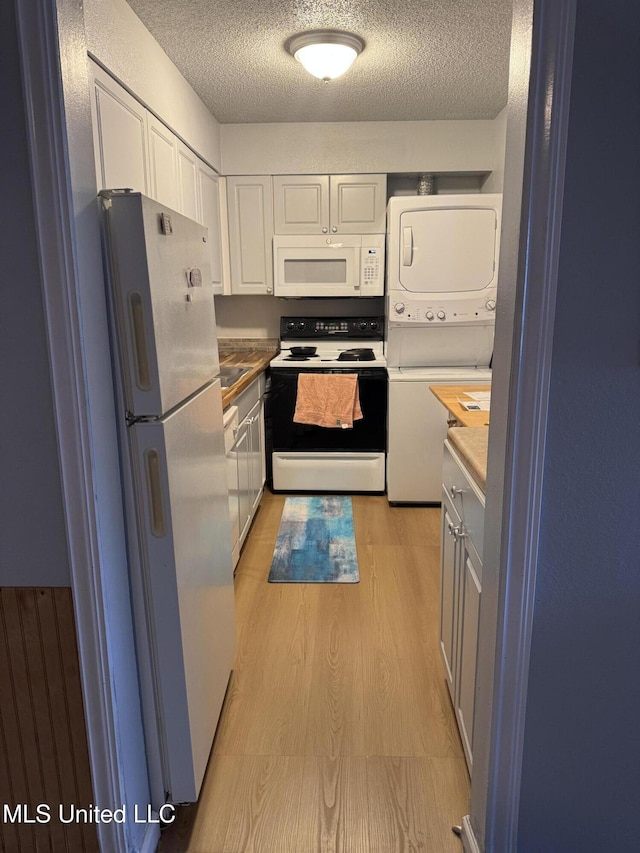 245 Mcdonnell Ave Unit 231, Biloxi, MS 39531 - kitchen with white appliances, stacked washer / drying machine, white cabinetry, a textured ceiling, and light wood-style flooring