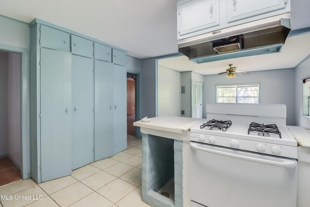 3008 Papania Ln, Gulfport, MS 39501 - kitchen featuring white range with gas stovetop, a ceiling fan, light tile patterned floors, under cabinet range hood, and light countertops