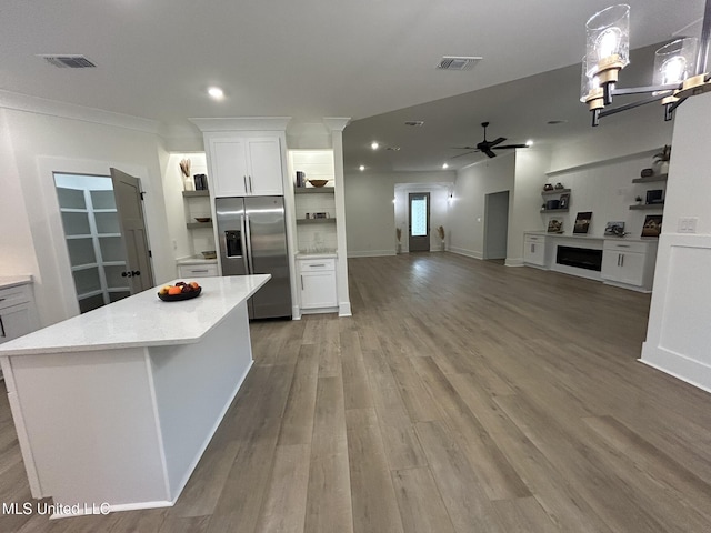 3076 Highland Ave, Diberville, MS 39540 - kitchen featuring stainless steel refrigerator with ice dispenser, open shelves, ceiling fan, a fireplace, and white cabinetry