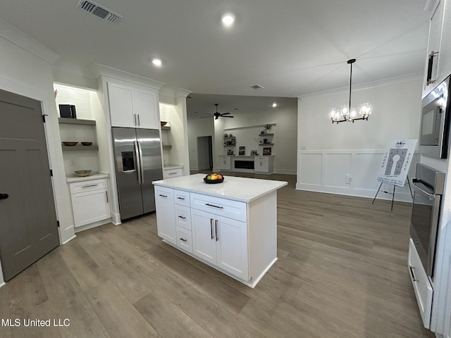 3076 Highland Ave, Diberville, MS 39540 - kitchen featuring stainless steel appliances, a ceiling fan, white cabinetry, a kitchen island, and wood finished floors